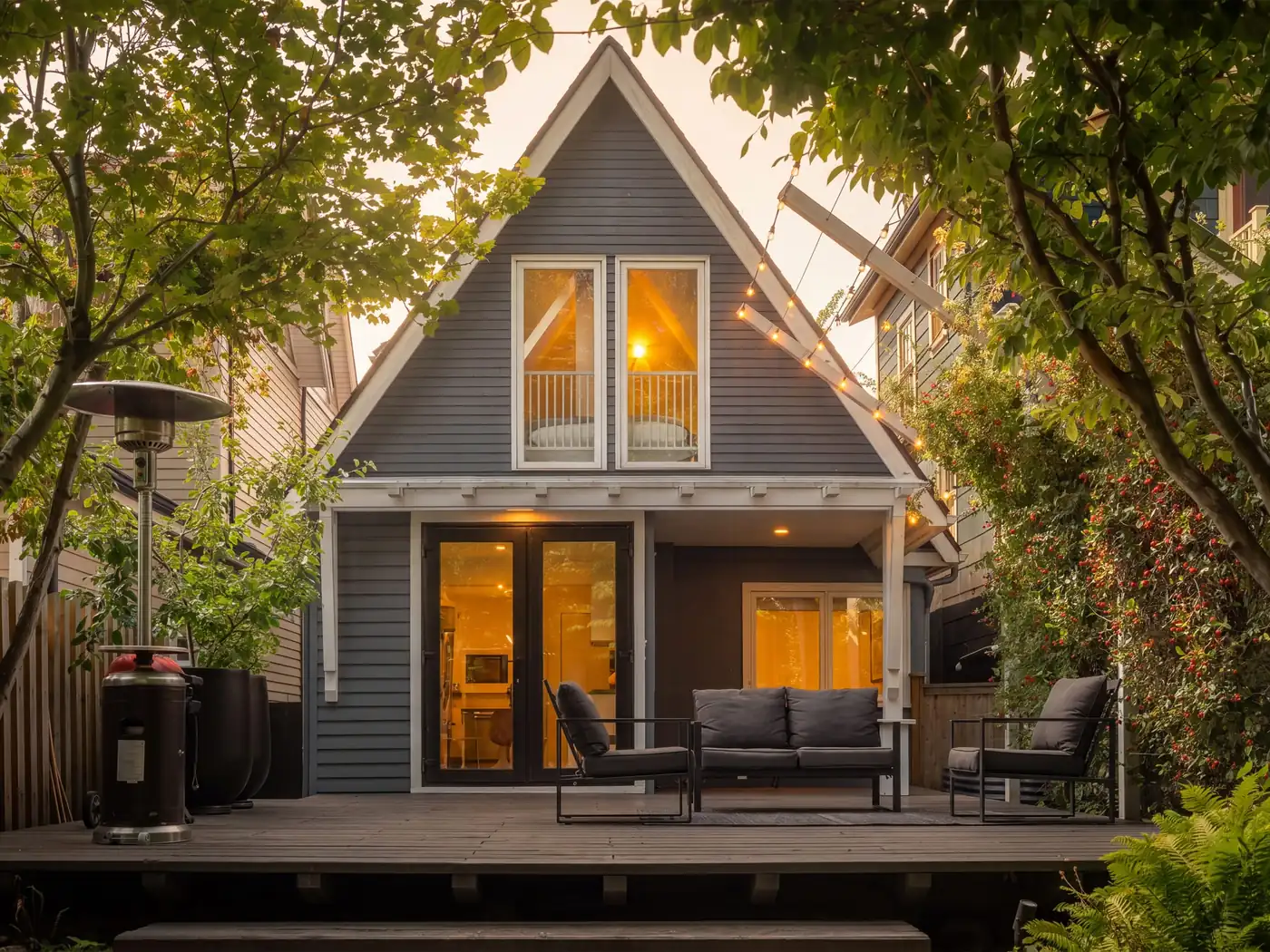 Twilight exterior of a Vancouver home photographed by Omidia, warm interior light and string lights over the deck